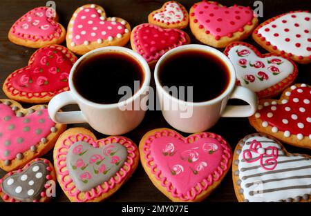 Zwei Tassen heißer Kaffee unter einem Haufen wunderschöner herzförmiger, königlicher Kekse mit Glasmuster Stockfoto