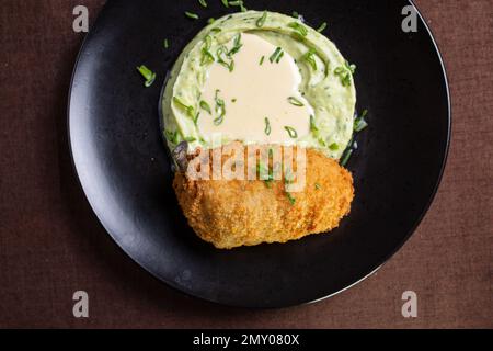 Kiew Kotelett mit Kartoffelpüree auf einem schwarzen Teller Stockfoto