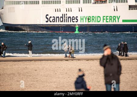 04. Februar 2023, Mecklenburg-Vorpommern, Warnemünde: Kinderwagen gehen unter blauem Himmel und Sonnenschein am Ostseestrand von Warnemünde, im Hintergrund verlässt eine Ostseefährte den Meereskanal in Richtung Ostsee. Die Winterferien beginnen an diesem Wochenende in Mecklenburg-Vorpommern. Foto: Frank Hormann/dpa Stockfoto