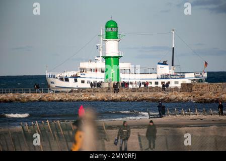 04. Februar 2023, Mecklenburg-Vorpommern, Warnemünde: Kinderwagen gehen unter blauem Himmel und Sonnenschein am Strand und Pier von Warnemünde, im Hintergrund verlässt ein Passagierschiff den Seekanal in Richtung Ostsee. Die Winterferien beginnen an diesem Wochenende in Mecklenburg-Vorpommern. Foto: Frank Hormann/dpa Stockfoto