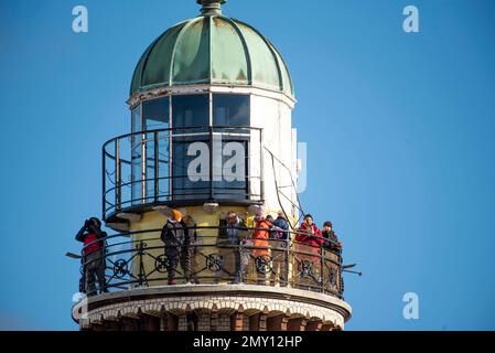 04. Februar 2023, Mecklenburg-Vorpommern, Warnemünde: Tagesbesucher stehen auf der Aussichtsplattform vom Leuchtturm in Warnemünde unter blauem Himmel und Sonnenschein. Die Winterferien beginnen an diesem Wochenende in Mecklenburg-Vorpommern. Foto: Frank Hormann/dpa Stockfoto