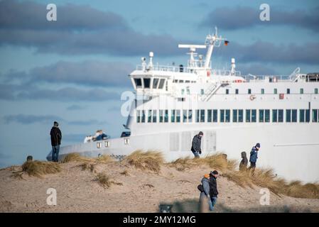 04. Februar 2023, Mecklenburg-Vorpommern, Warnemünde: Kinderwagen gehen unter blauem Himmel und Sonnenschein am Ostseestrand von Warnemünde, im Hintergrund verlässt eine Ostseefährte den Meereskanal in Richtung Ostsee. Die Winterferien beginnen an diesem Wochenende in Mecklenburg-Vorpommern. Foto: Frank Hormann/dpa Stockfoto