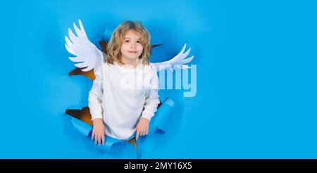 Valentinstag. Kleiner Kinderengel im Papierloch. Porträt eines süßen Kindes mit Engelsflügeln. Amor-Junge. Stockfoto