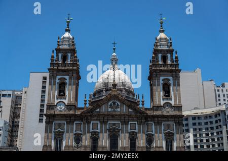 Blick auf das obere Ende der Kirchenfassade von Candelaria im Viertel Centro, umgeben von Geschäftsgebäuden unter dem sonnigen blauen Himmel am Sommernachmittag. Stockfoto