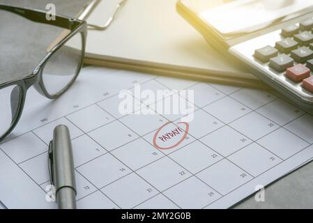 Lohn- und Gehaltsabrechnung und Zahltag mit Rechner und Kalender. Stockfoto