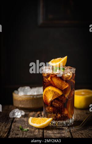 Cuba Libre in einem Glas mit braunem Rum, Cola, Minze und Zitrone auf dunklem Hintergrund. Cuba Libre oder Long Island Eistee Cocktail mit starken Getränken Stockfoto
