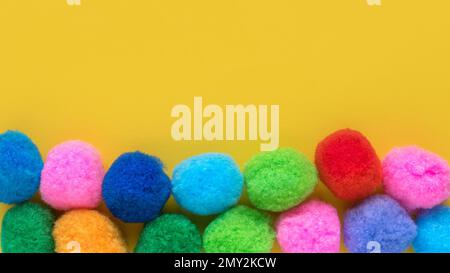 Bunte Baumwollkugeln auf gelbem Hintergrund mit Kopierbereich. Stockfoto