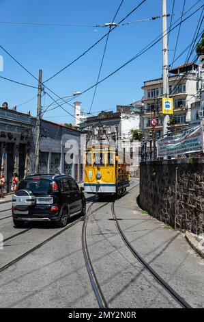 Eine Straßenbahn von Santa Teresa, die zurück zum Centro-Viertel fährt, während Sie von einem Auto auf der Almirante Alexandrino Straße unter dem blauen Himmel am Sommernachmittag verfolgt werden. Stockfoto