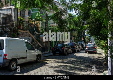 Autos parken auf der kopfsteingepflasterten Straße Ladeira de Santa Teresa vor einigen Häusern im Viertel Santa Teresa unter dem sonnigen blauen Himmel am Sommernachmittag Stockfoto