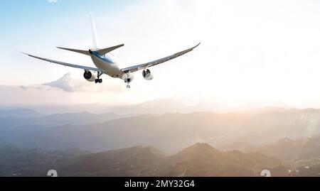 Passagier gewerbliches Flugzeug, das über den Bergen fliegt Stockfoto