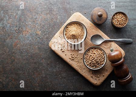 Organisch getrocknete Koriandersamen (Coriandrum sativum) und Pulver auf rustikalem Hintergrund. Gesunde Ernährung, indische Gewürze, Geschmack, Vitamin. Stockfoto