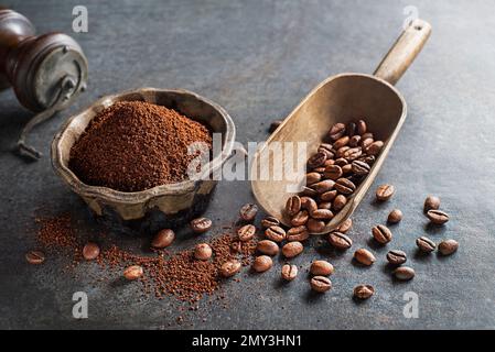 Kaffeebohnen und frisch gemahlenes Kaffeepulver auf grauem Steinhintergrund – Nahaufnahme Stockfoto