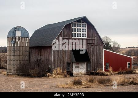 Eine rustikale Scheune und ein Silo mit einem daran befestigten roten Schuppen an einem Wintertag in Franconia, Minnesota, USA. Stockfoto