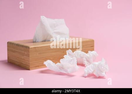 Halter mit Papiertüchern und gebrauchten, zerknitterten Servietten auf pinkfarbenem Hintergrund Stockfoto