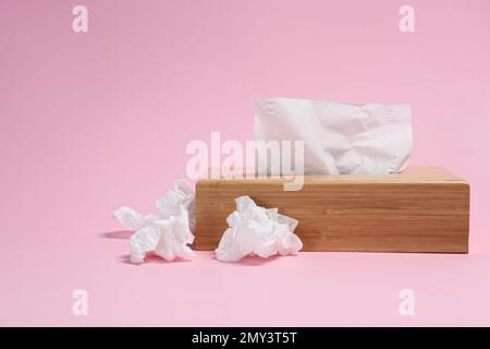 Halter mit Papiertüchern und gebrauchten, zerknitterten Servietten auf pinkfarbenem Hintergrund Stockfoto