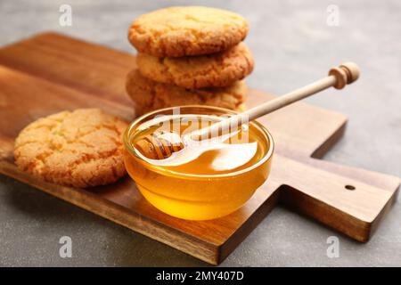 Leckerer Honig und Kekse auf hellgrauem Tisch Stockfoto