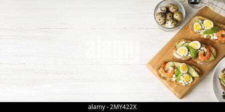 Flach liegend mit leckeren Bruschettas auf weißem Holztisch, Platz für Text. Bannerdesign Stockfoto