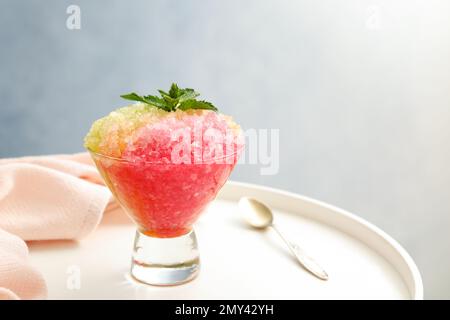 Rasierendes Eis in einer Glas-Dessertschüssel auf einem weißen Tisch, Nahaufnahme Stockfoto