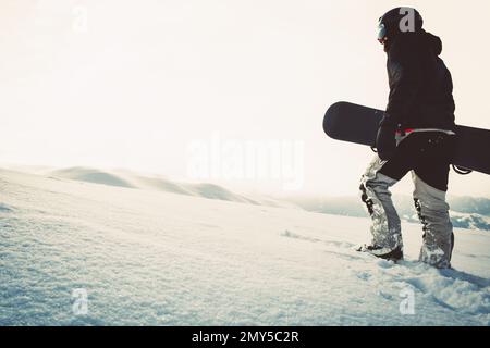 Snowboarder in einer kompletten Schutzausrüstung für extremes Freeride Snowboarden beim Snowboarden. Isoliert auf grauem, weißem Schneefall Stockfoto