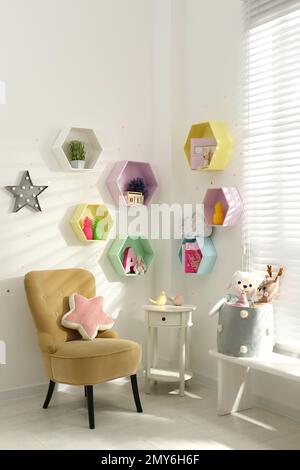 Sechseckige Regale an der weißen Wand im Kinderzimmer. Innendesign Stockfoto