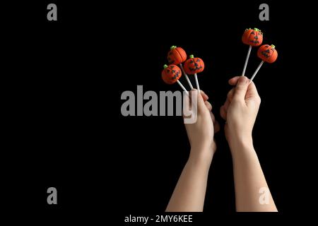 Frau mit köstlichen Kürbiskuchen und Platz für Text auf schwarzem Hintergrund, Nahaufnahme. Halloween-Feier Stockfoto