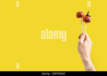 Frau mit köstlichen Kürbiskuchen und Platz für Text auf gelbem Hintergrund, Nahaufnahme. Halloween-Feier Stockfoto