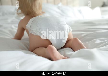 Süßes kleines Baby in Windel im Schlafzimmer, konzentriere dich auf die Beine Stockfoto