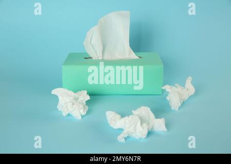 Gebrauchte Papiertücher und Schachtel auf hellblauem Hintergrund Stockfoto