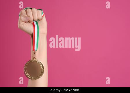 Frau mit Goldmedaille auf pinkfarbenem Hintergrund, Nahaufnahme. Raum für Design Stockfoto