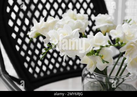 Wunderschöne weiße Freesia-Blumen in Vase auf Sessel, Schließfach Stockfoto