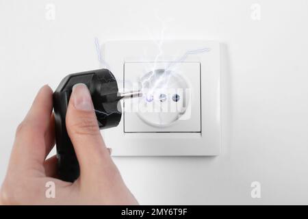 Eine Frau, die beim Ausstecken einen elektrischen Schlag erleidet, eine Nahaufnahme Stockfoto