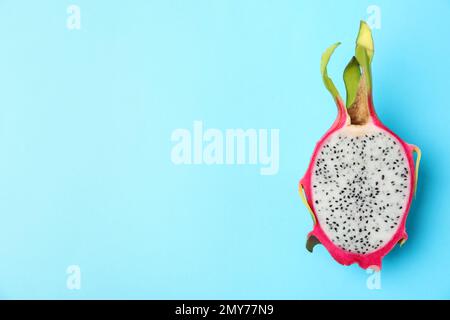 Die Hälfte der köstlichen reifen Drachenfrucht (Pitahaya) auf hellblauem Hintergrund, Draufsicht. Platz für Text Stockfoto