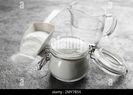Backpulver in Glasgefäß auf grauem Tisch Stockfoto