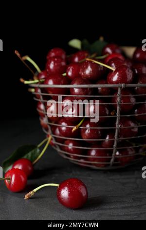 Süße, saftige Kirschen mit Wassertropfen auf dem schwarzen Tisch Stockfoto