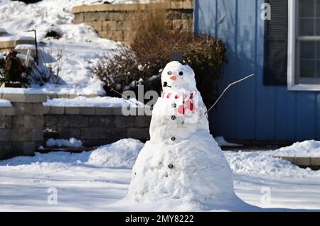 Streamwood, Illinois, USA. Ein großer Schneemann sitzt allein in einem Vorgarten eines vorstädtischen Chicagoer Hauses nach einem nassen Midwestern der Vereinigten Staaten Schneesturm. Stockfoto