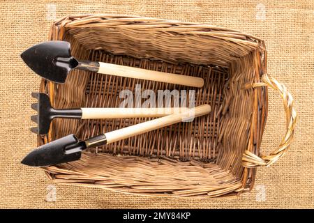 Gartenwerkzeug mit Holzgriff in Korb auf Jutelleder, Makro, Draufsicht. Stockfoto