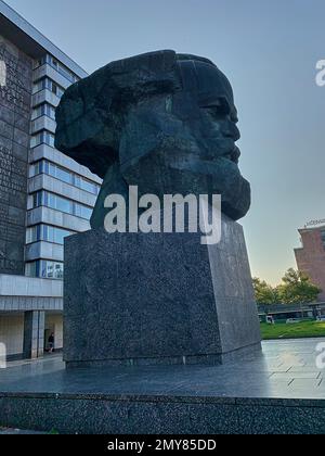 Chemnitz, Deutschland - 09 08 2021: Denkmal von Karl Marx vor einem Gebäude, das den Text seiner kommunistischen These in grossen Buchstaben in s zeigt Stockfoto