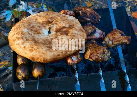 Ostkaukasische Brotlavash, Fleisch und gegrillte Kartoffeln auf einem Picknick in der Natur Stockfoto