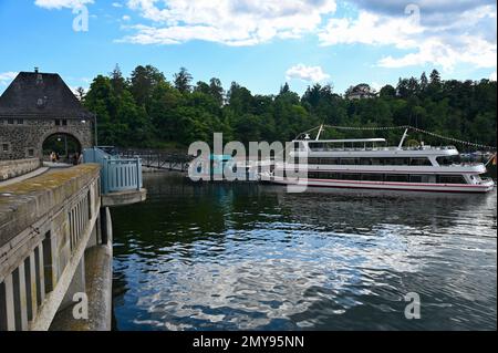 Blick auf den Edersee mit einem Teil der Staumauer, mit einem großen Ausflugsboot am Anlegeplatz, mit blauem Himmel und Wolken, in Hessen, Deutschland Stockfoto