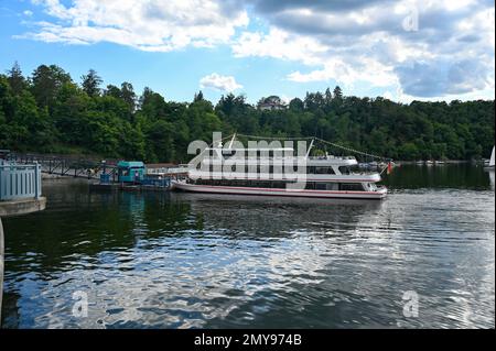 Blick auf den Edersee mit einem Teil der Staumauer, mit einem großen Ausflugsboot am Anlegeplatz, mit blauem Himmel und Wolken, in Hessen, Deutschland Stockfoto