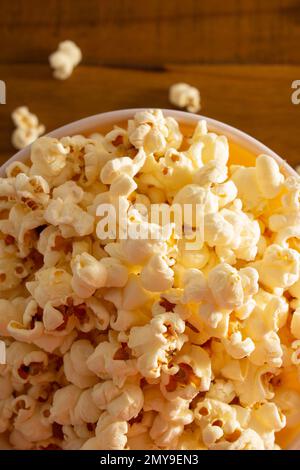 Goiania, Goias, Brasilien – 04. Februar 2023: Detail einer Schüssel voller Popcorn, wobei einige auf einem Holztisch verstreut sind. Stockfoto