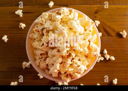 Goiania, Goias, Brasilien – 04. Februar 2023: Eine Schüssel voller Popcorn mit etwas verschüttetem Popcorn auf dem Holztisch. Stockfoto