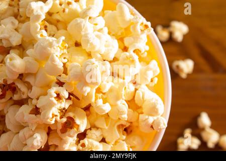 Goiania, Goias, Brasilien – 04. Februar 2023: Detail einer Schüssel voller Popcorn, wobei einige auf einem Holztisch verstreut sind. Stockfoto