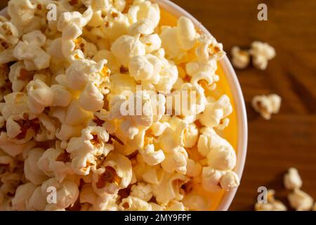 Goiania, Goias, Brasilien – 04. Februar 2023: Detail einer Schüssel voller Popcorn, wobei einige auf einem Holztisch verstreut sind. Stockfoto