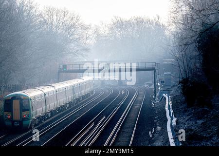 Ein nebiger, frostiger Tag und ein Zug fährt zum Bahnhof Victoria in London, England Stockfoto