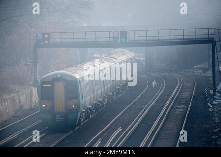 Ein nebiger, frostiger Tag und ein Zug fährt zum Bahnhof Victoria in London, England Stockfoto