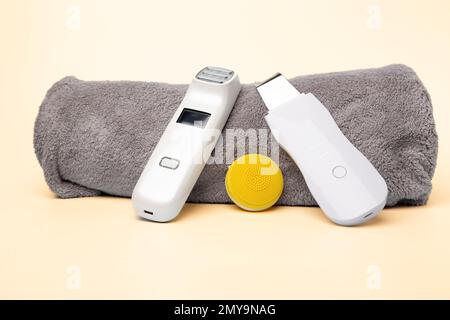 Das Kit für Gesichtsreinigungsgeräte auf einem grauen Handtuch auf hellrosa Hintergrund Stockfoto