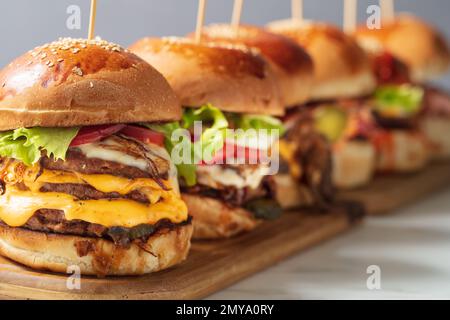 Viele verschiedene Burger mit Zutaten auf einer Holzplatte Stockfoto