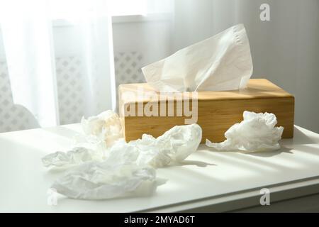 Gebrauchte Papiertücher und Holzhalter auf dem Tisch in der Nähe des Fensters Stockfoto