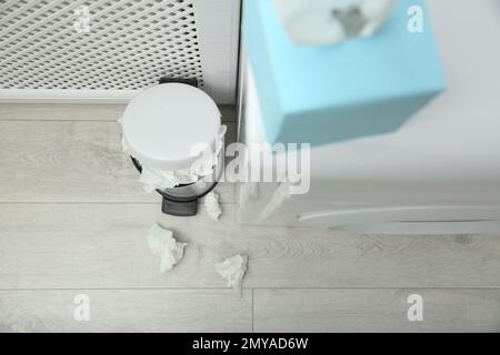 Gebrauchte Papiertücher und Abfalleimer auf Holzboden, über der Ansicht Stockfoto